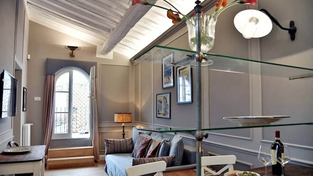 Une pièce avec un lit, une table garnie de nourriture et de boissons, une lampe et une fenêtre donnant sur un beau paysage.