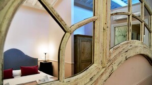 Une chambre à coucher avec un lit, une table de chevet et un miroir qui reflète la pièce.