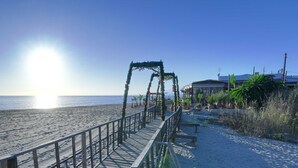 A wooden pier leading to a beach with a clear sky and a building in the background. - 1104 Charming Beachfront Apartment on Golden Beach (Marbella)