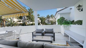 A covered outdoor seating area with a table and chairs, a sofa, and a bench. - 1104 Charming Beachfront Apartment on Golden Beach (Marbella)