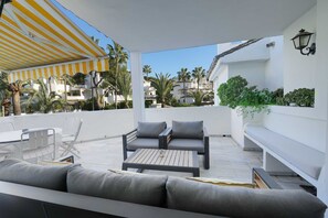 Un espace extérieur abrité, aménagé avec une table et des chaises, un canapé et un banc.