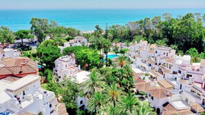 A coastal residential area with white buildings, a swimming pool, and a view of the sea. - 1104 Charming Beachfront Apartment on Golden Beach (Marbella)