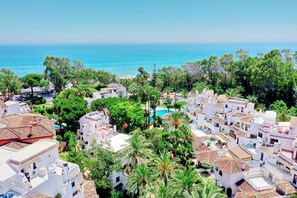 Un quartier résidentiel situé sur la côte, avec des bâtiments blancs, une piscine et une vue sur la mer.