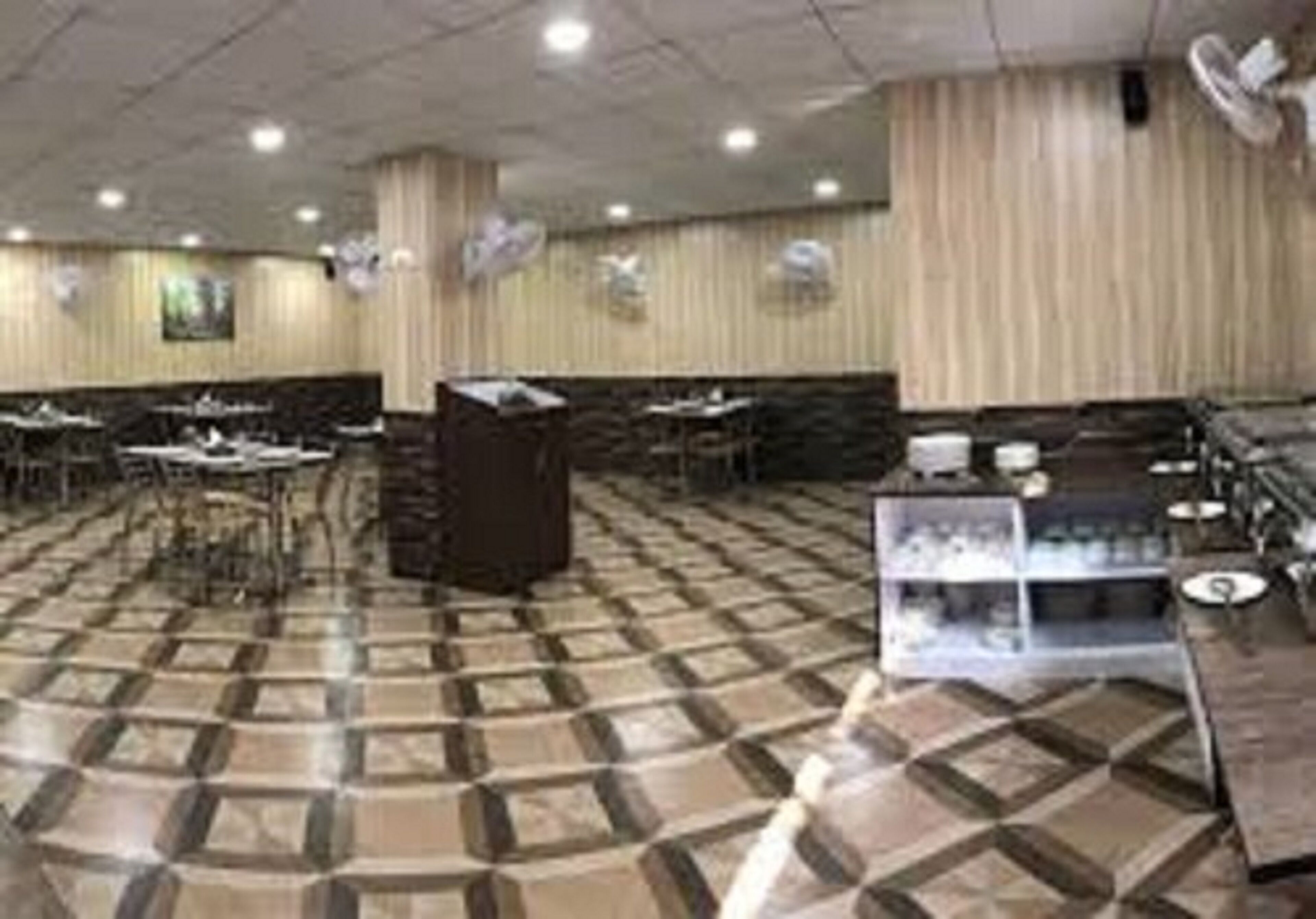 Un restaurante espacioso con suelo de cuadros, varias mesas y una barra de servicio.