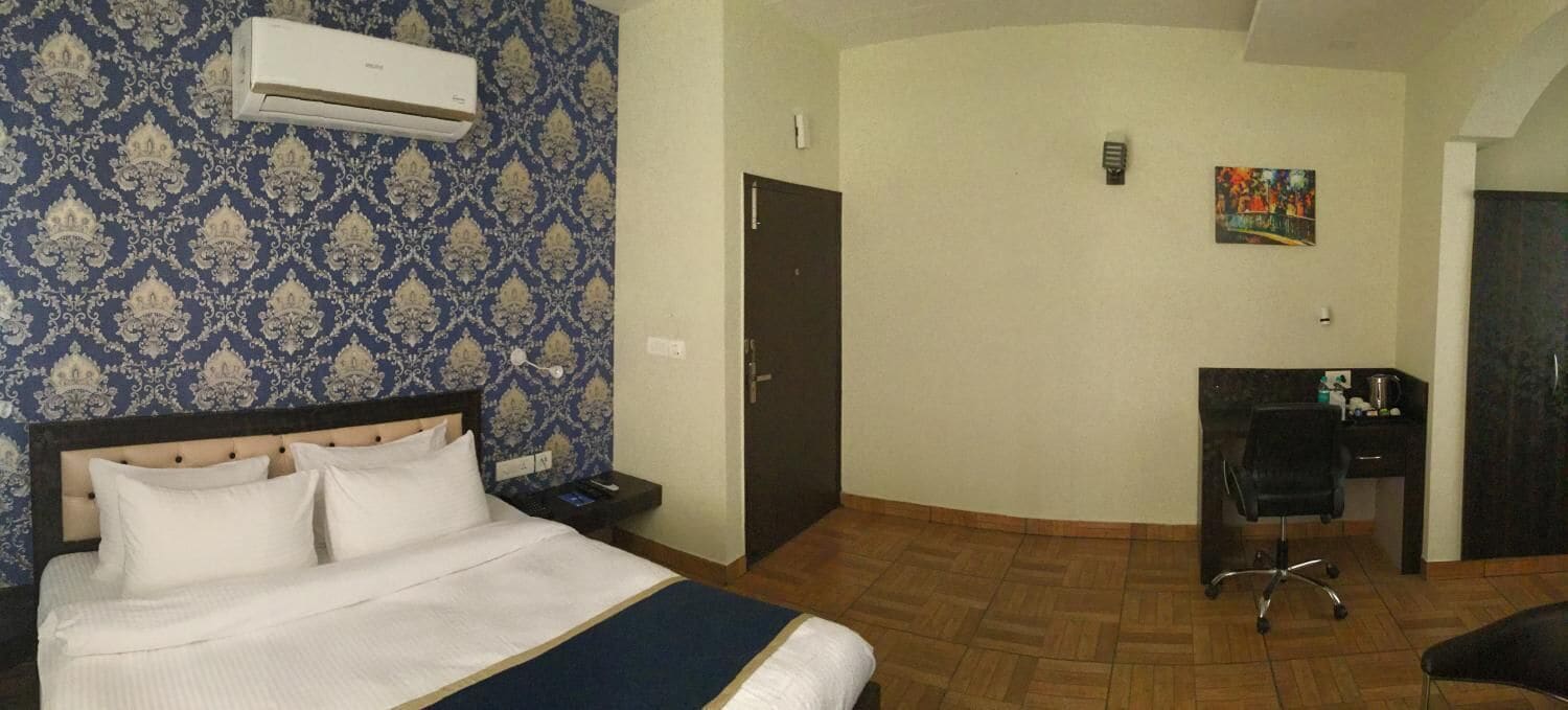 Una habitación de hotel con cama, escritorio, silla, aire acondicionado y puerta.