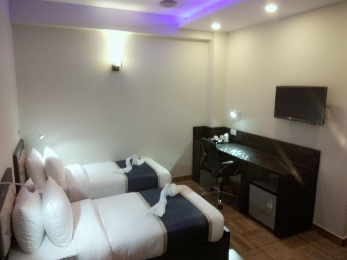 A room with two beds, a desk, and a TV on the wall.