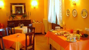 A dining area with tables set for breakfast, a mirror, wall sconces, and decorative plates.