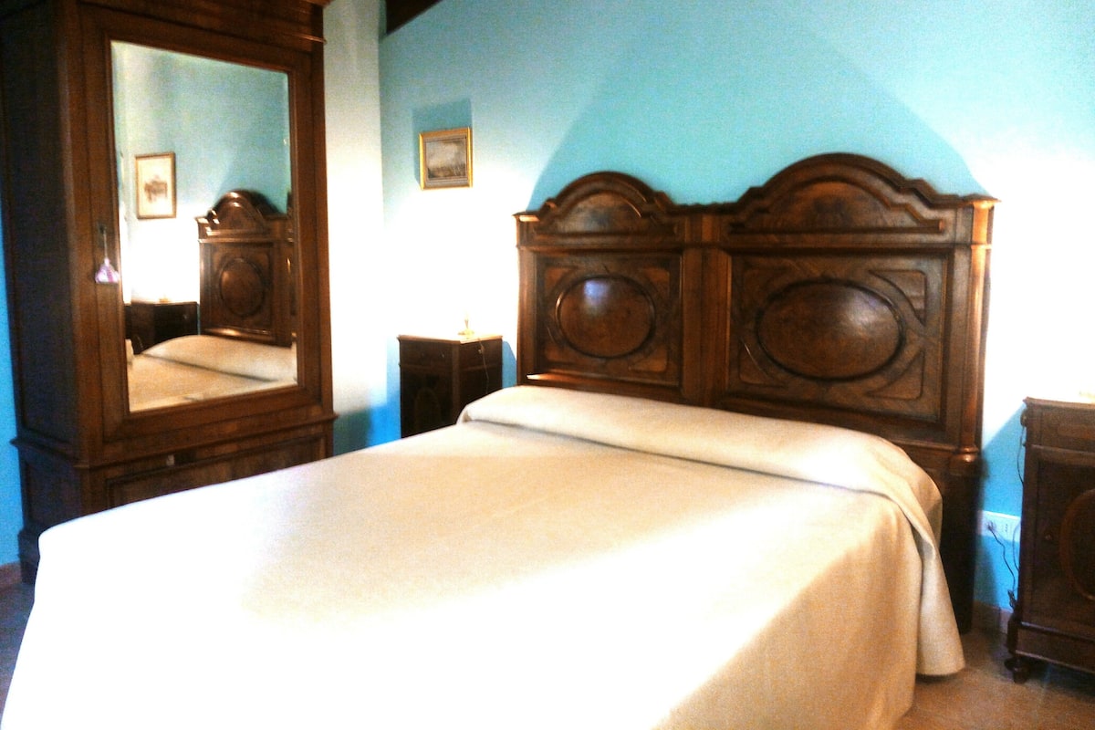 A bedroom with a wooden bed, a large mirror, and a nightstand.