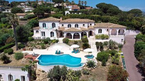Una villa grande con piscina, varios balcones y un jardín bien cuidado.