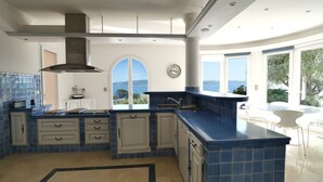 Una cocina moderna con azulejos azules, una isla grande y vistas al mar.