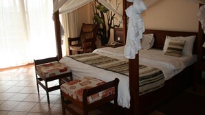 A four-poster canopy bed with a mural of trees on the wall behind it. - Ryan's Bay Hotel (Mwanza)