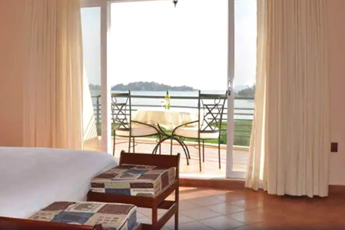 Ein Hotelzimmer mit Bett, einem kleinen Tisch und Blick auf einen Balkon mit Tisch und Stühlen.