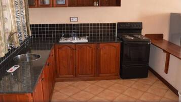 Una cocina con muebles de madera, una estufa negra y un salpicadero de azulejos.