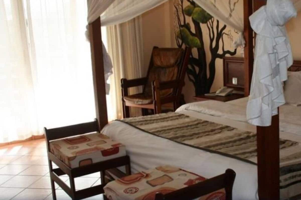 Ein Schlafzimmer mit Himmelsbett, einem Sessel, einem Nachttisch und einer Wandmalerei.