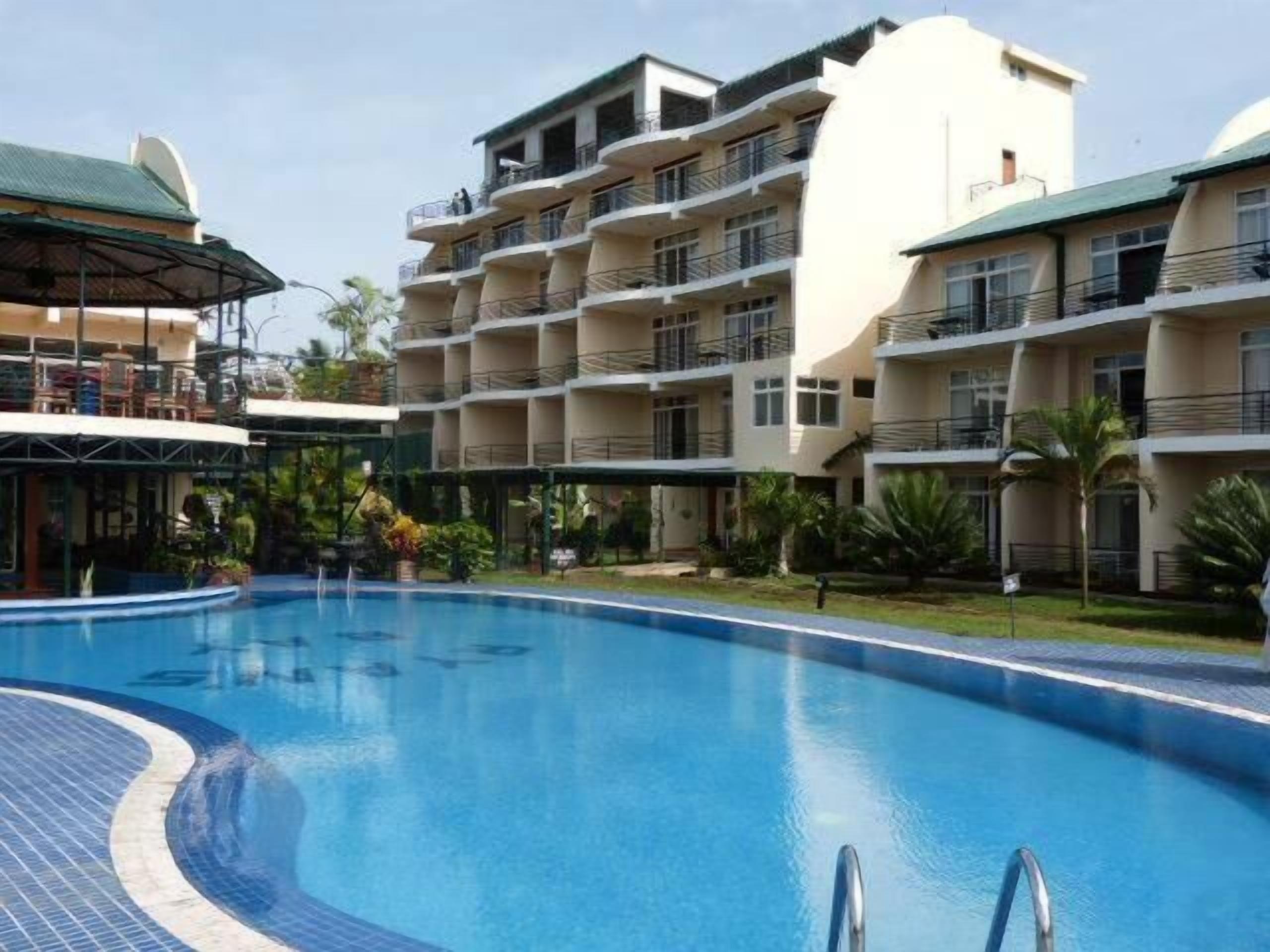 A hotel with a swimming pool, multiple balconies, and a covered outdoor area.
