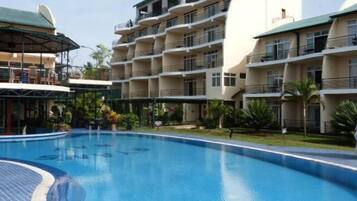 A hotel with a swimming pool, multiple balconies, and a covered outdoor area.