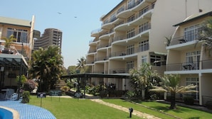 A hotel with multiple balconies, a swimming pool, and a well-maintained lawn. - Ryan's Bay Hotel (Mwanza)