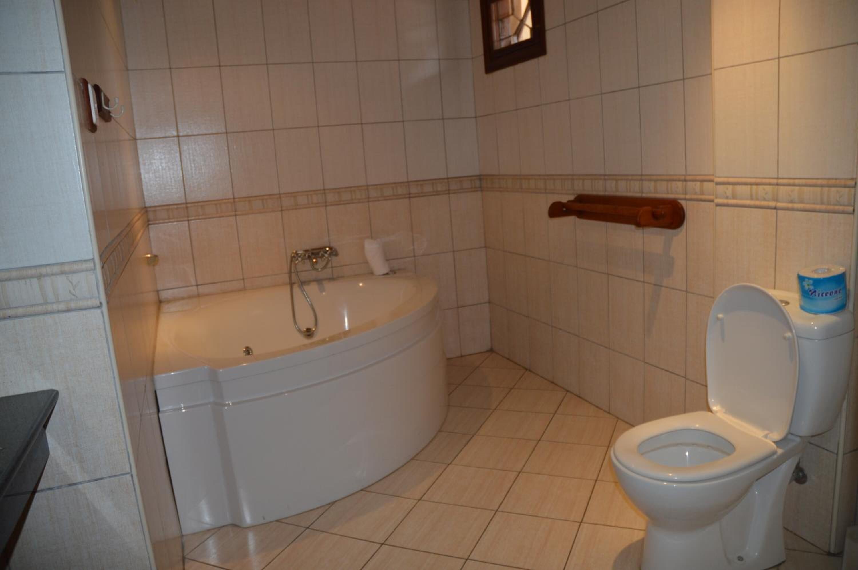 A bathroom with a bathtub, toilet, and a towel rack.