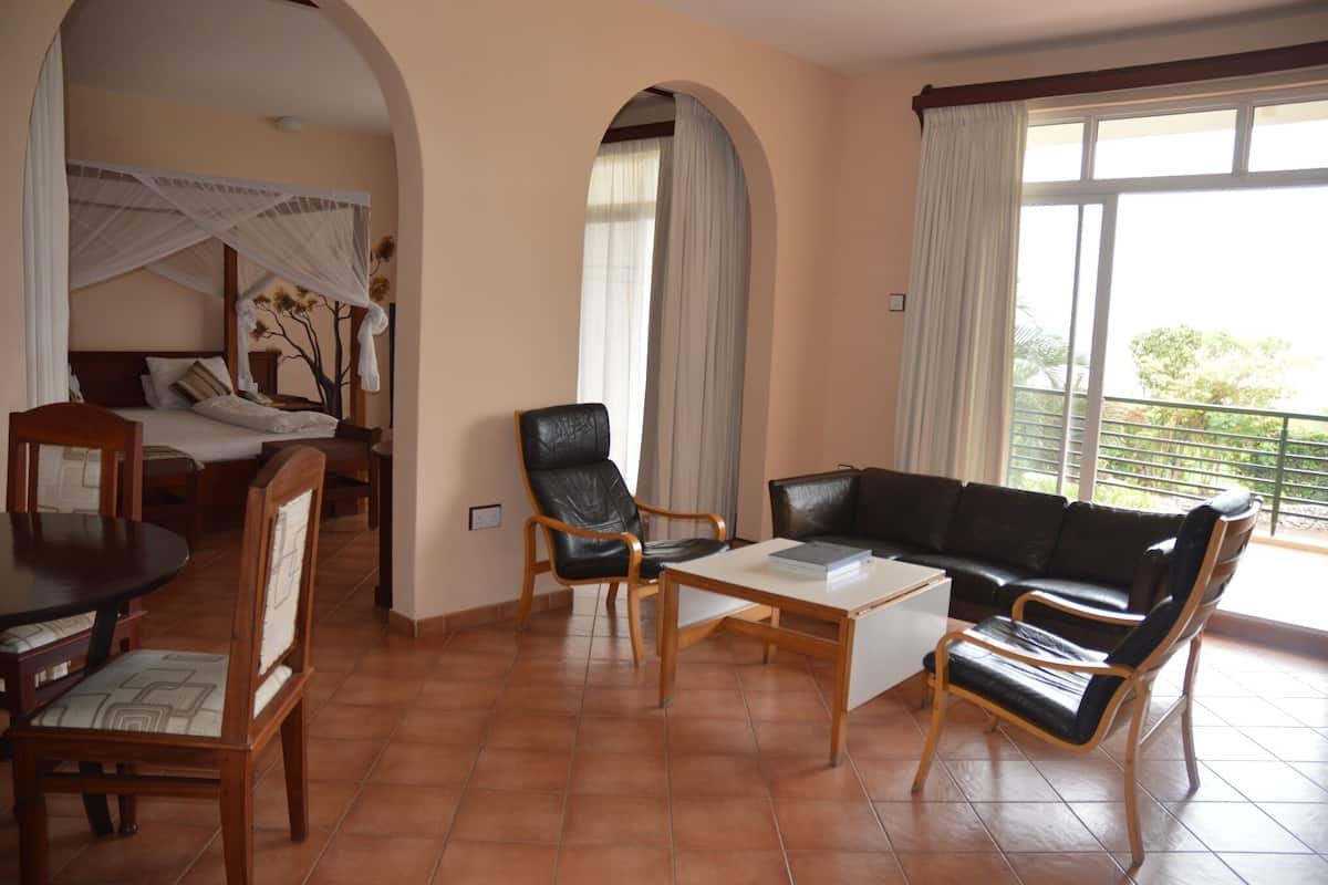Ein Hotelzimmer mit Bett, Esstisch, Sofa und einem Balkon mit Blick.