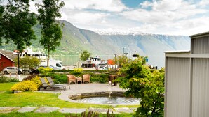 A lakeside patio with outdoor seating, a small fountain, and a view of mountains. - Walaker Hotel (Luster)