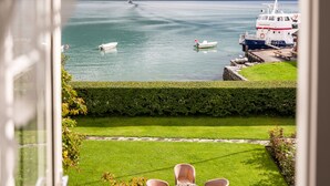 A view of a lake with boats, a dock, and a grassy area with wicker chairs. - Walaker Hotel (Luster)