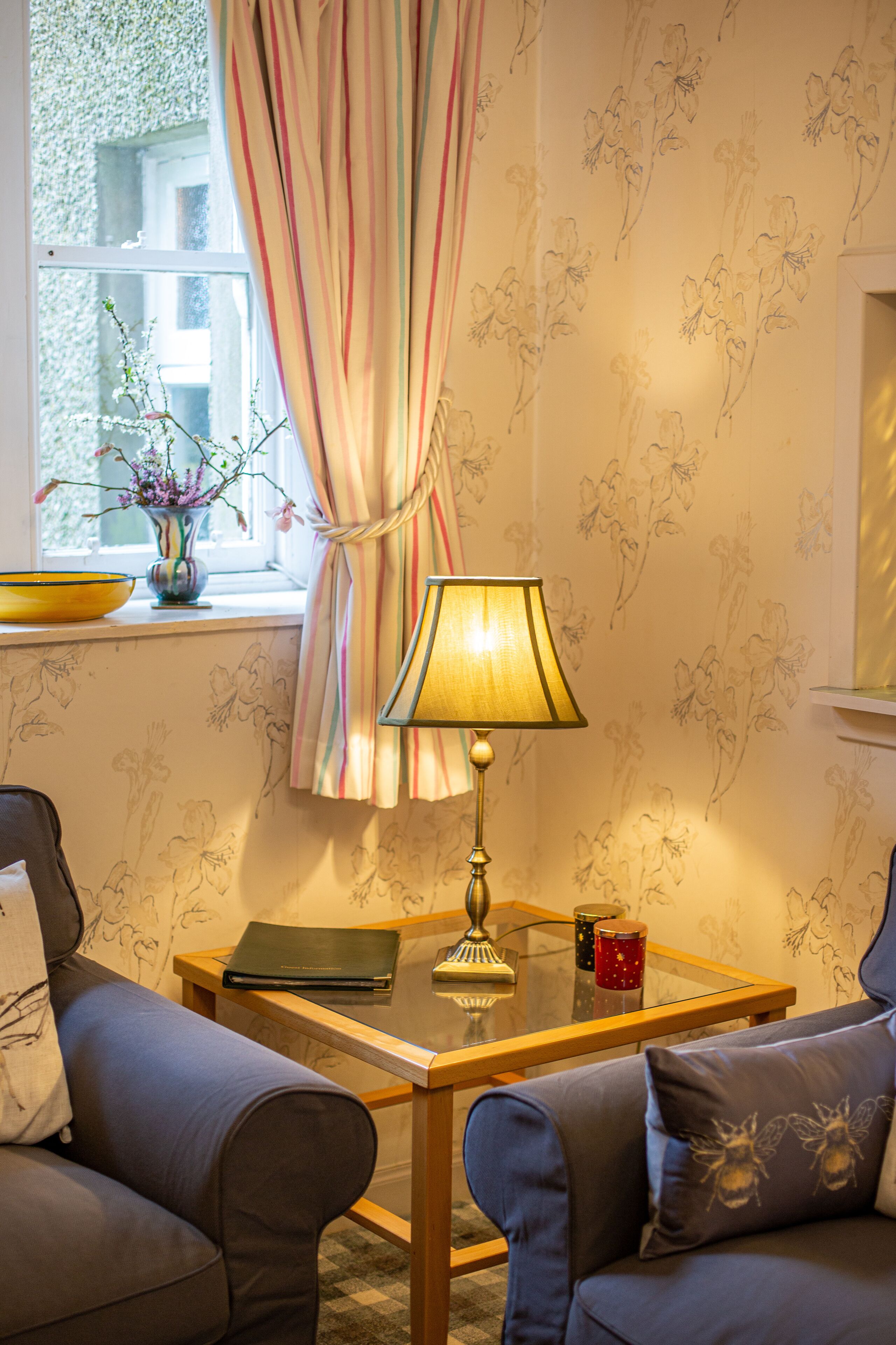 A cozy room with a sofa, a small table, a lamp, and a window with curtains.