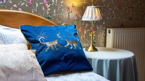 A bedroom with a bed, a blue pillow with animal designs, a lamp, and a floral wallpaper. - GARDEN COTTAGE, near St Andrews.Glorious, country location. New prices available (cupar fife)