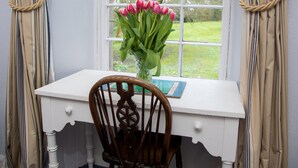 A white desk with a vase of pink tulips, a wooden chair, and a window with a view of a green landscape. - GARDEN COTTAGE, near St Andrews.Glorious, country location. New prices available (cupar fife)