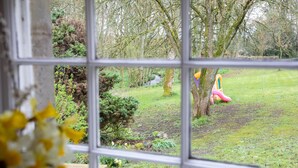 A view through a window of a garden with a wooden bench, a small pond, and a pink slide. - GARDEN COTTAGE, near St Andrews.Glorious, country location. New prices available (cupar fife)