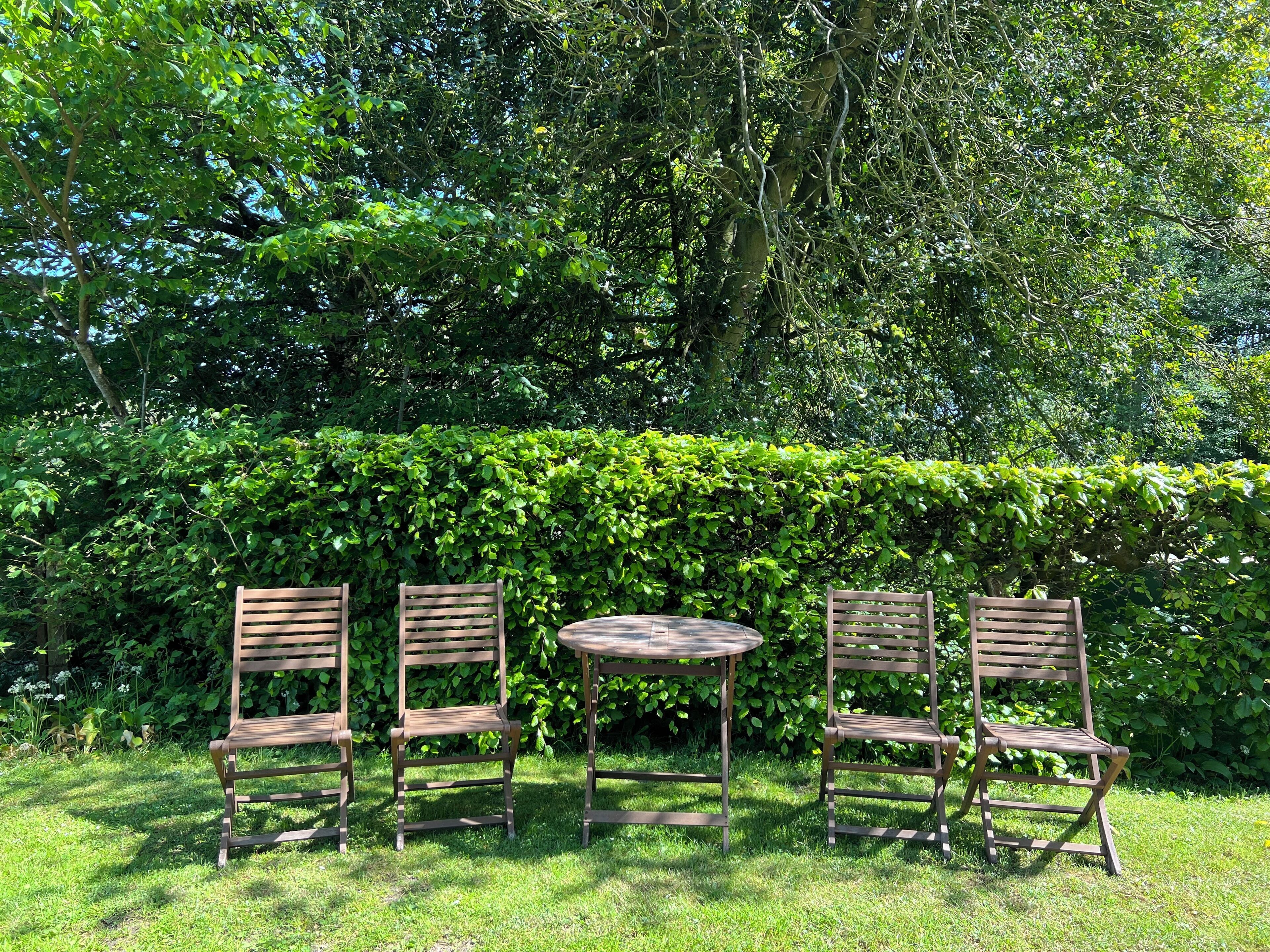 A garden with a wooden table and four chairs.