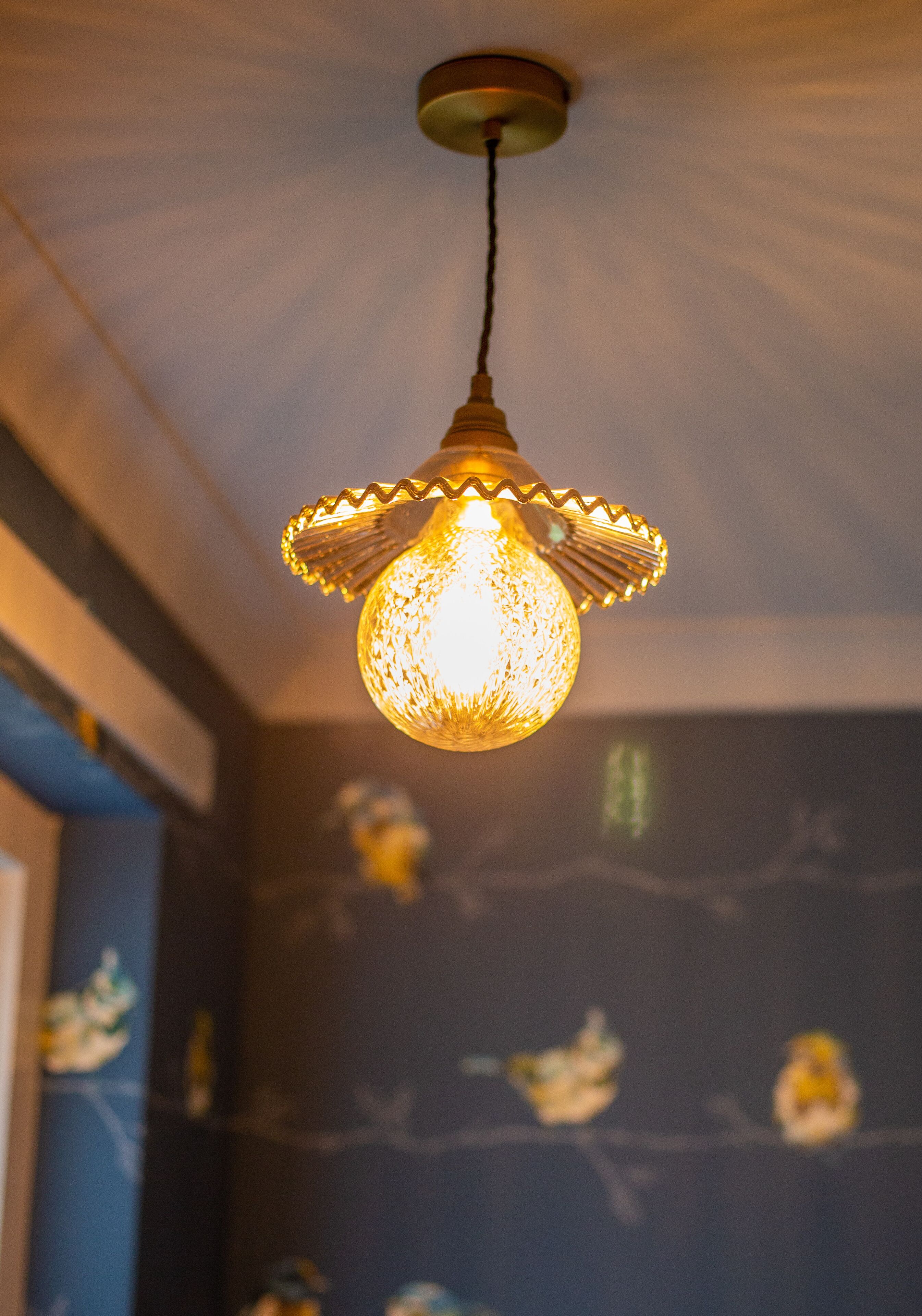 A hanging light fixture with a textured glass shade and a metallic base.