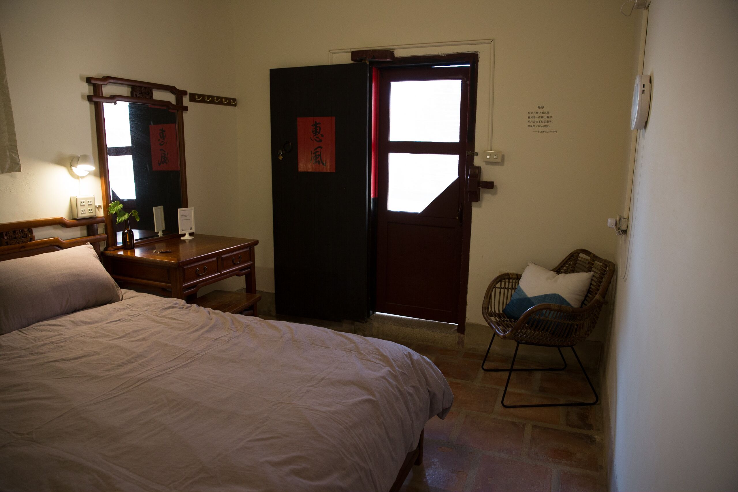 A bedroom with a bed, a dresser, a chair, and a door with a window.