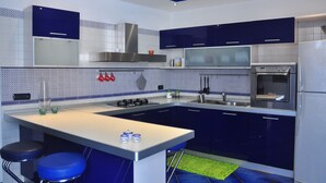 Une cuisine moderne avec des meubles bleu foncé, un plan de travail blanc et des appareils électroménagers en acier inoxydable.