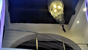 Un intérieur moderne avec un escalier, un coin repas et un luminaire au plafond original.