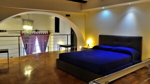 Une chambre à coucher avec un lit, une table de chevet, une lampe et une porte en arc de cercle.
