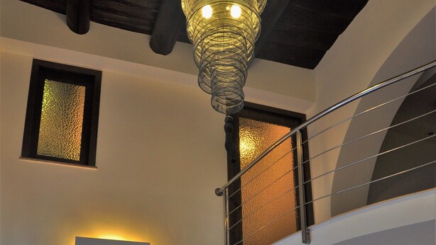 Un intérieur moderne avec un canapé, un luminaire mural original et un escalier.