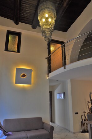Ein modernes Interieur mit einer Couch, einer außergewöhnlichen Wandleuchte und einer Treppe.