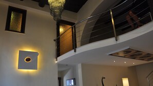 Un intérieur à plusieurs niveaux, avec un escalier, un luminaire fixé au mur et une sculpture de girafe.