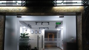 An indoor entrance with a glass door, a red carpet, potted plants, and clocks indicating different time zones. - R&G Suite (Ho Chi Minh City)