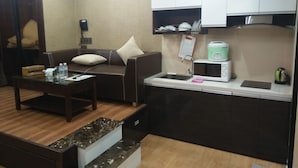 A compact living space with a sofa, coffee table, and a kitchenette area. - R&G Suite (Ho Chi Minh City)