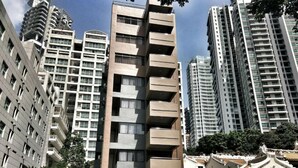 Un moderno edificio de apartamentos con varios pisos y balcones, rodeado de otros edificios altos.