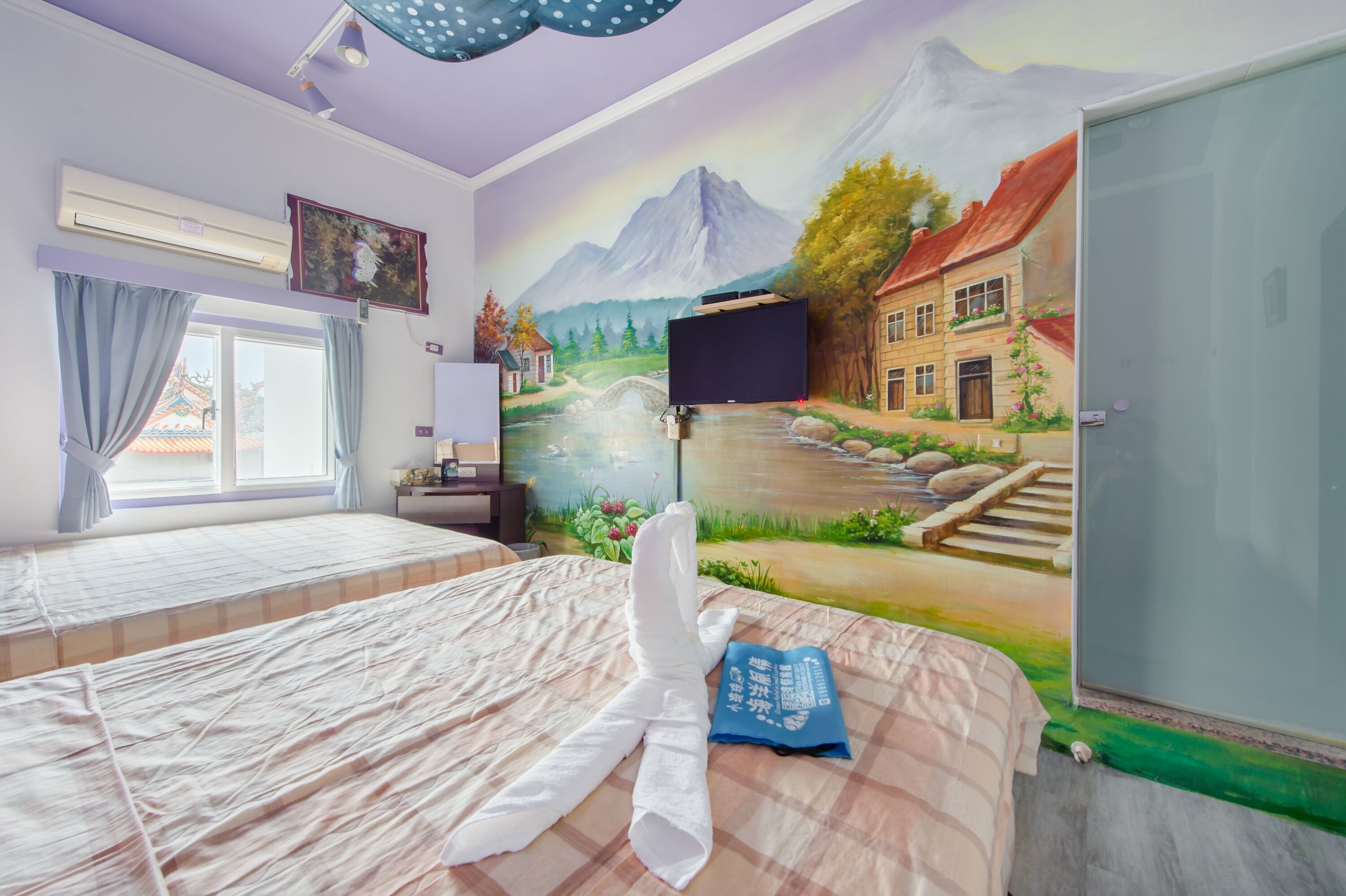 Habitación de hotel con dos camas, un mural de un paisaje montañoso, un televisor y una puerta.