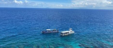 Una vista despejada del océano, con dos barcos y un litoral rocoso en primer plano.