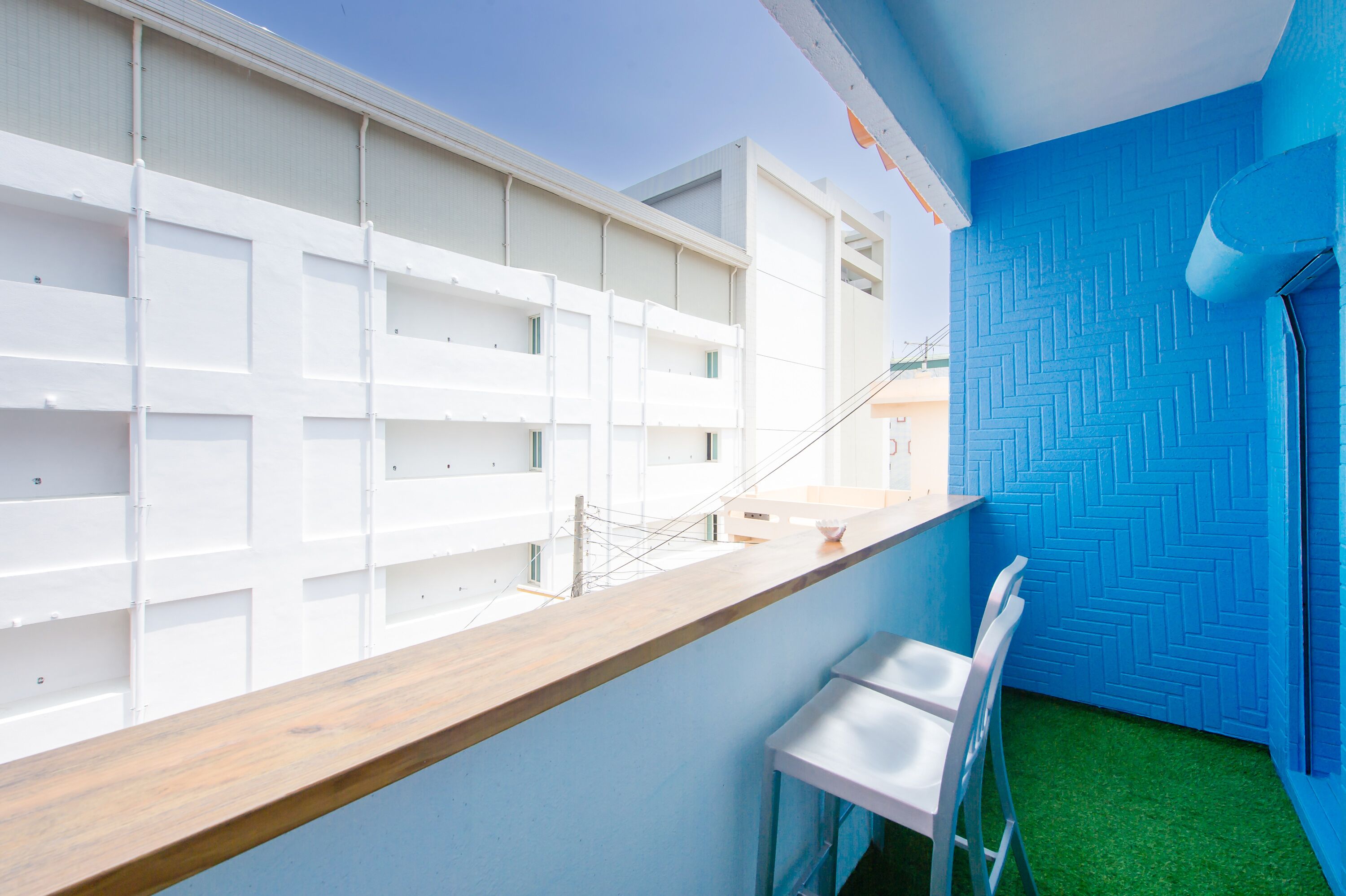 Un interior moderno con mostrador de madera, sillas blancas y pared azul texturizada.