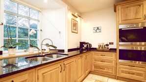 A modern kitchen with wooden cabinets, a stainless steel sink, and two built-in ovens. - A Georgian Masterpiece Steps from Stirling  (Stirling)