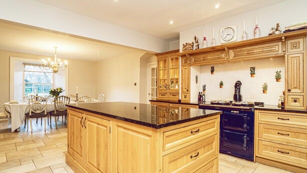 A spacious kitchen with wooden cabinets, a central island, and a dining area with a chandelier. - A Georgian Masterpiece Steps from Stirling  (Stirling)