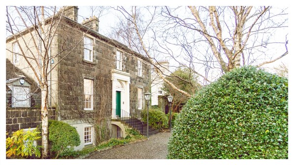 A traditional stone building with a green door, a stone staircase, and a gravel path.