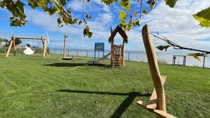 A grassy outdoor area with a swing set and a climbing structure. - Europarcs Markermeer (Bovenkarspel)