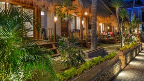 A resort with thatched-roof structures, outdoor seating, and lush greenery. - Village Vibes Lombok (Kuta)