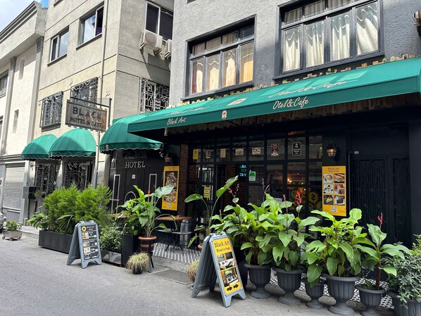 A hotel with a green awning, outdoor seating, and potted plants. - Black Art Otel (Istanbul)